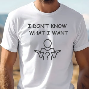 May include: White t-shirt with the text "I DON'T KNOW WHAT I WANT" above a stick figure with outstretched arms and a question mark. The shirt is being worn by a person.