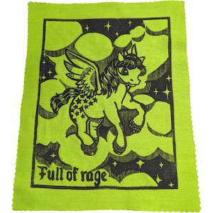 May include: A neon green fabric square featuring a black illustration of a winged unicorn with stars and clouds. The text "Full of rage" is printed at the bottom. The design is a bold, graphic style.