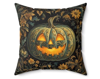 Puede incluir: Cojín cuadrado con un diseño de calabaza de Halloween. La calabaza es verde azulado con intrincados detalles dorados y una cara tallada. El fondo es negro con patrones florales dorados y verde azulado, ideal para decoración.