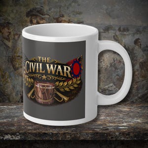 May include: White ceramic mug with a Civil War-themed design. The design includes the text "THE CIVIL WAR" in gold, a drum, a flag, and other decorative elements. The mug has a standard handle. The background is a dark grey.