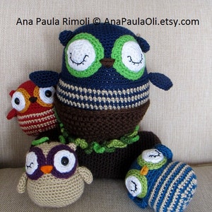 May include: Four crocheted owls in different colors and patterns. The largest owl is blue with green eyes and a brown body. The other owls are red, beige, and blue with white eyes.