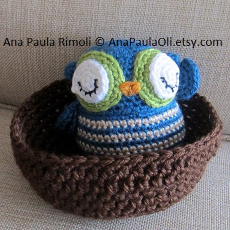 May include: A blue and green crocheted owl toy sitting in a brown crocheted basket.