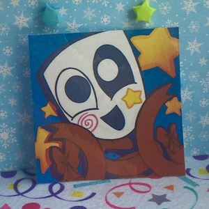 May include: A square art print featuring a white mask with large dark eyes and a spiral cheek design. The mask is surrounded by brown ribbon-like shapes and yellow stars against a blue background. The illustration has a bold, graphic style.