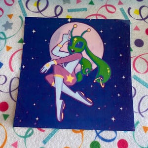 May include: A square art print featuring a green alien character with long ears and antennae, wearing a purple outfit with yellow stars. The character is posed against a large pale moon and a dark blue starry night sky background with small white stars.