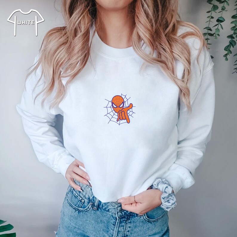 May include: White sweatshirt with a small orange and purple embroidered image of Spiderman in a web.