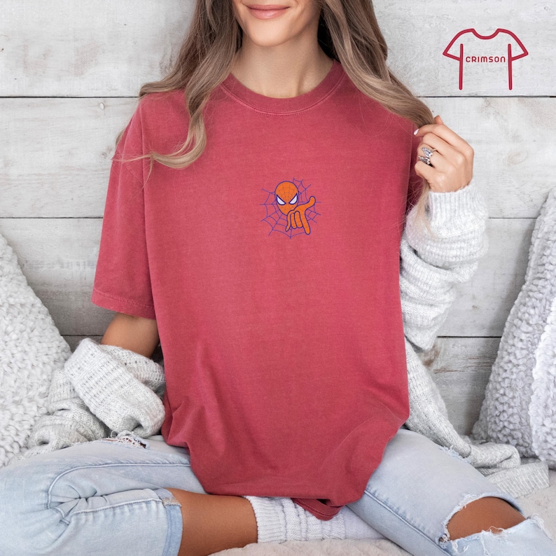 May include: A red t-shirt with a cartoon image of Spider-Man's head with a web behind it.