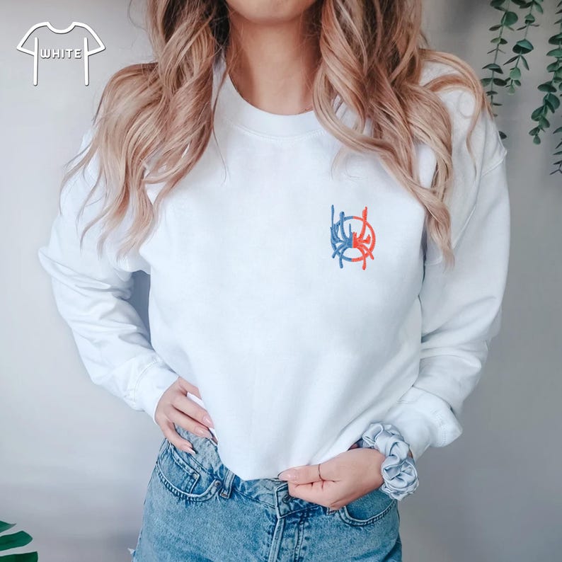 May include: White long-sleeved sweatshirt with a red, blue and white embroidered design on the front.