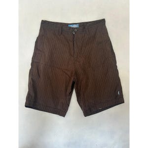 May include: Brown striped shorts with a button closure and a small logo near the hem. The shorts have a classic design with vertical stripes. The shorts are made of a durable fabric.