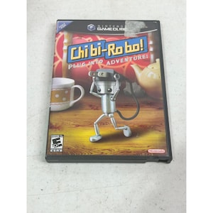 以下が含まれることがあります： ロボットのキャラクターが特徴の「Chibi-Robo! Plug Into Adventure!」のNintendo GameCubeビデオゲームケース。ケースは黒い縁取りで、ESRBレーティングと任天堂のロゴが含まれています。背景にはティーセットが描かれています。