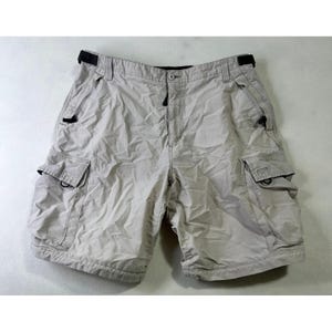 Può includere: Pantaloncini cargo beige chiaro con più tasche e chiusura con bottoni. I pantaloncini hanno una vestibilità rilassata e dettagli con passanti neri. Questi pantaloncini sono adatti per attività all'aperto.
