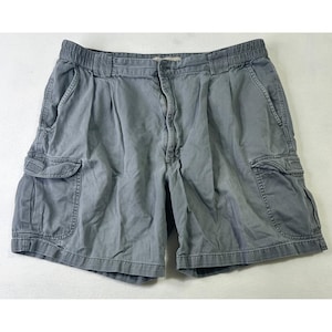 May include: Gray cargo shorts with multiple pockets and a button closure. The shorts have a relaxed fit and an elastic waistband. The fabric appears to be a durable cotton blend, suitable for casual wear. The shorts are laid flat on a white surface.