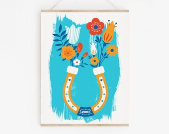 May include: A colorful illustration of a horseshoe with flowers in each end. The horseshoe is yellow with white polka dots and the flowers are red, orange, yellow, and white. The background is a blue watercolor wash with the word "LUCKY" written in blue and white.