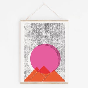 Beautiful abstract landscape scene Sun Mountains wall art, silkscreen art print. Palm Springs and desert vibes featuring a textured dark gray background and a large bright pink sun overlaying a set of orange mountains. Size 16x22 inches.