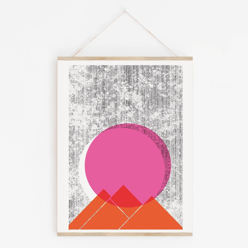 Beautiful abstract landscape scene Sun Mountains wall art, silkscreen art print. Palm Springs and desert vibes featuring a textured dark gray background and a large bright pink sun overlaying a set of orange mountains. Size 16x22 inches.