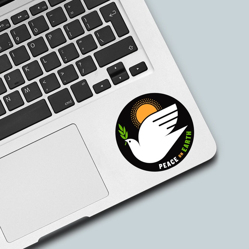 May include: A black and white sticker with a white dove holding an olive branch, a yellow sun, and the text "PEACE ON EARTH".