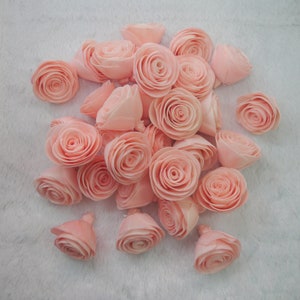 Op de afbeelding: Een verzameling van lichtroze papieren rozen, gerangschikt in een cluster op een witte achtergrond. De rozen zijn gemaakt van papier en hebben een delicate, gelaagde uitstraling.