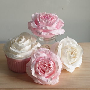 May include: Four artificial roses, two pink and two white, arranged on a wooden surface. The roses are made of fabric and have a realistic appearance.