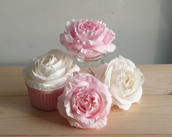 May include: Four artificial roses, two pink and two white, arranged on a wooden surface. The roses are made of fabric and have a realistic appearance.