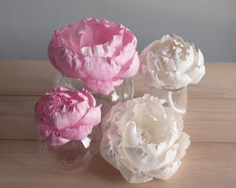 Pode incluir: Quatro flores de peônia artificiais em dois tons de rosa e dois tons de branco, cada uma repousando em um recipiente de vidro transparente. As flores apresentam pétalas delicadas e em camadas com acabamento fosco, dispostas em um grupo compacto.
