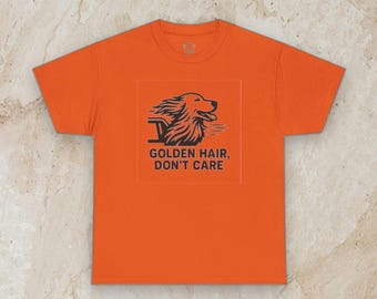May include: A bright orange short-sleeved t-shirt featuring a dark graphic of a dog with flowing fur and the text "GOLDEN HAIR, DON'T CARE" printed in a bold, sans-serif font centered on the chest area of the garment.