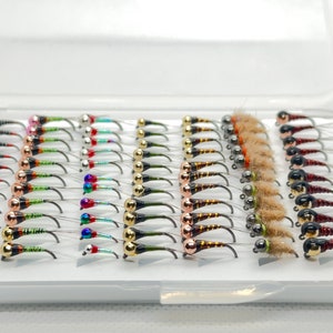 Może przedstawiać: Białe plastikowe pudełko wypełnione różnymi przynętami muchowymi. Przynęty są wykonane z koralików i piór w różnych kolorach.