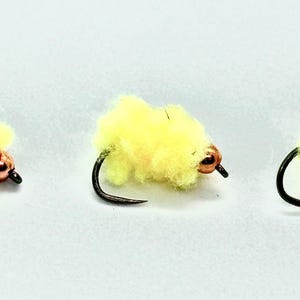Può includere: Tre esche da pesca a mosca gialle con perline arancioni. Le esche sono legate con un materiale soffice e hanno un amo nero.