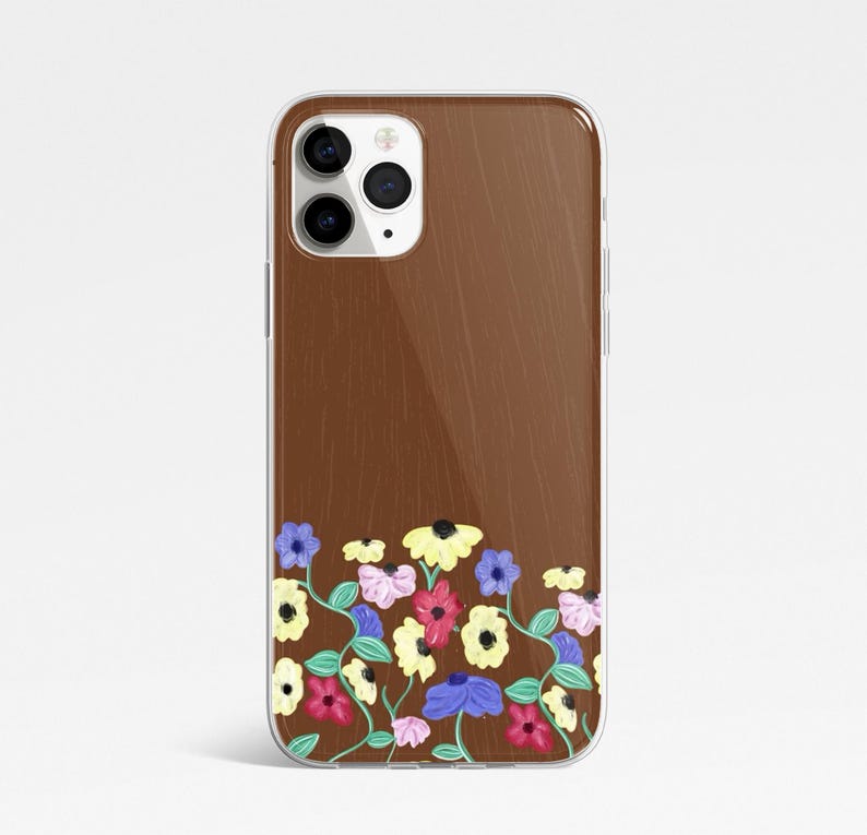 May include: A clear phone case with a brown wood grain effect. The bottom of the case features a colourful floral pattern with yellow, pink, blue, and white flowers. The case has a clear border.