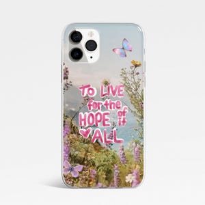 May include: Transparent phone case with a floral and butterfly design. The case has the text "To live for the hope of it all" in pink. The background shows a landscape with flowers and butterflies.