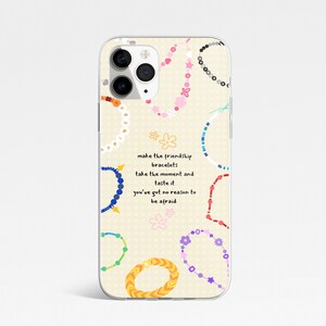 May include: A phone case with a cream background featuring colourful friendship bracelet designs and the text "make the friendship bracelets, take the moment and taste it, you've got no reason to be afraid."