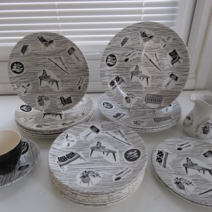 Può includere: Un set di stoviglie vintage della metà del secolo scorso con piatti, una tazza e un piattino e una lattiera. I piatti bianchi e grigi hanno un motivo unico di mobili e forme astratte. La tazza è nera.