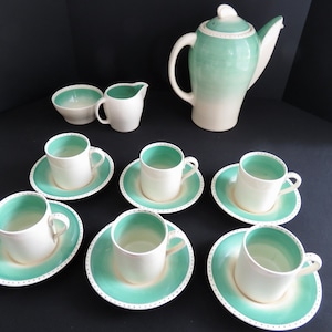 May include: A vintage tea set in white and seafoam green. The set includes a teapot, creamer, sugar bowl, and six cups with saucers. The saucers and the inside of the cups are seafoam green with a white dotted border. A classic tea set.