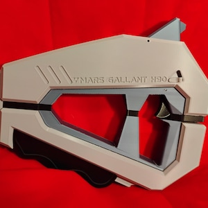 Puede incluir: Una pistola de juguete de plástico blanco y gris con detalles negros. La pistola tiene un mango y un gatillo. El texto "37 MARS GALLANT H300" está impreso en el lateral de la pistola.