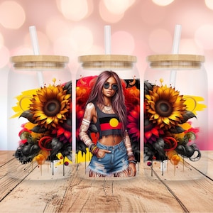 May include: Three clear glass tumblers with bamboo lids and straws. Each tumbler features a different design with sunflowers, an Aboriginal flag, and a woman wearing sunglasses.