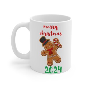 May include: White ceramic mug with a gingerbread man design and the text "merry christmas 2024".