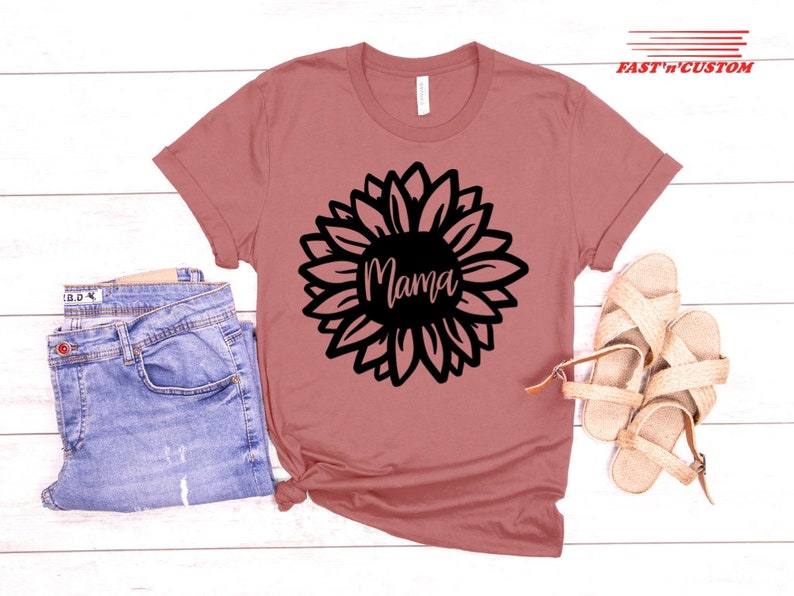 a t - shirt with a sunflower on it next to a pair of jeans