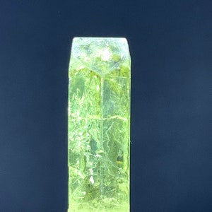Puede incluir: Un cristal transl&uacute;cido verde brillante con forma rectangular. El cristal est&aacute; sobre una superficie gris.