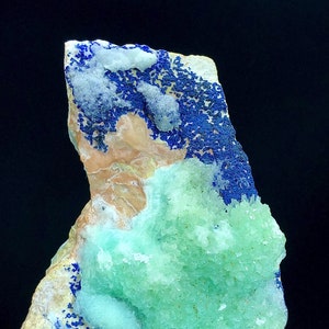 May include: A green and blue mineral specimen with a rough, textured surface. The specimen has a cluster of green crystals on one side and a layer of blue crystals on the other side.