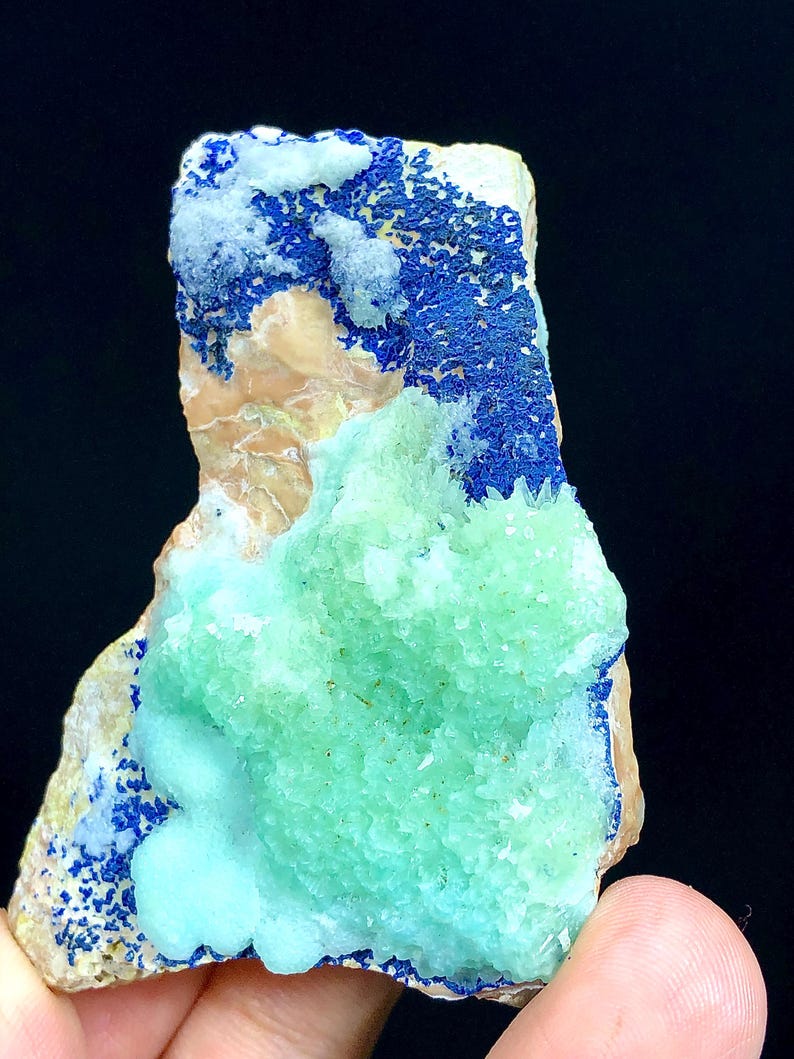 May include: A green and blue mineral specimen with a rough, textured surface. The specimen has a large, green, crystalline formation in the center, surrounded by a blue, crystalline formation.