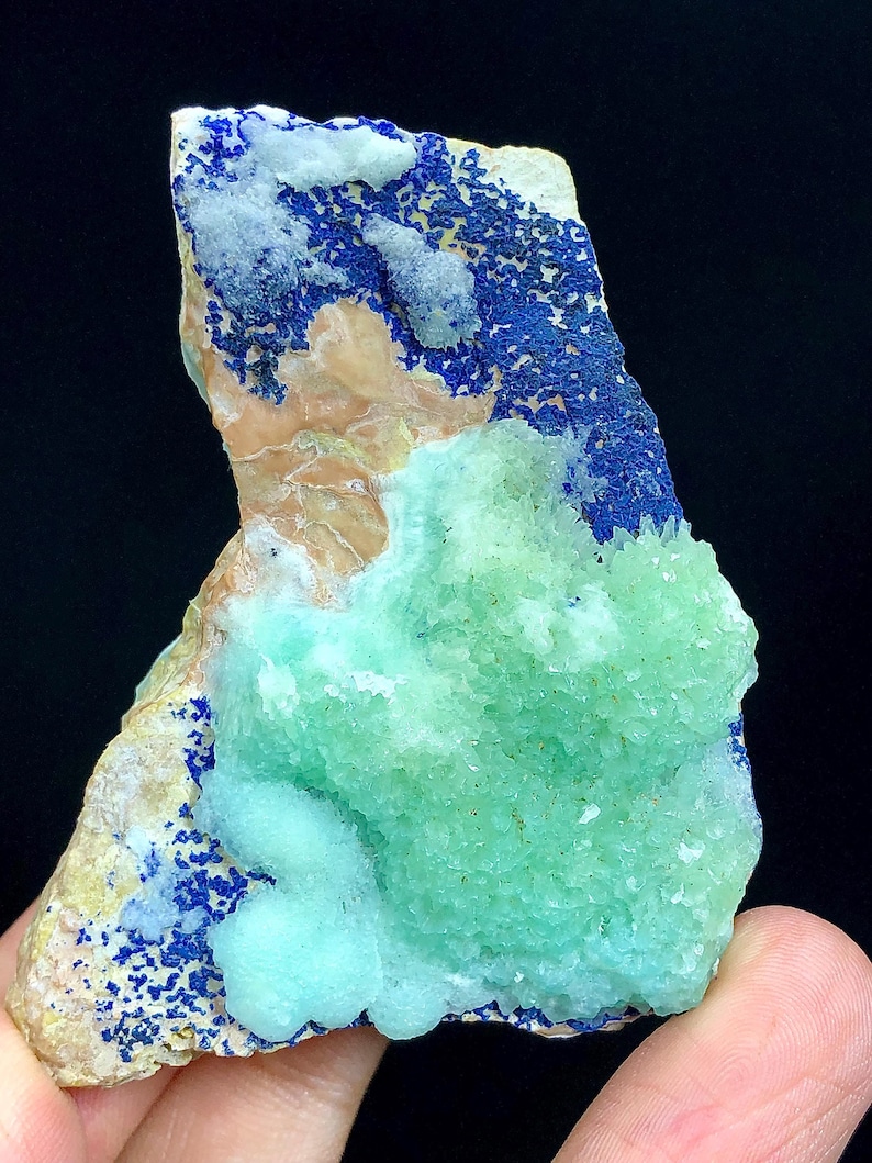 May include: A green and blue mineral specimen with a rough, textured surface. The specimen has a cluster of green crystals on one side and a layer of blue crystals on the other side.