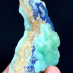 May include: A green and blue mineral specimen with a rough, textured surface. The mineral has a light green color with blue accents.