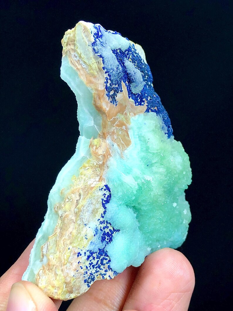 May include: A green and blue mineral specimen with a rough, textured surface. The mineral has a light green color with blue accents.