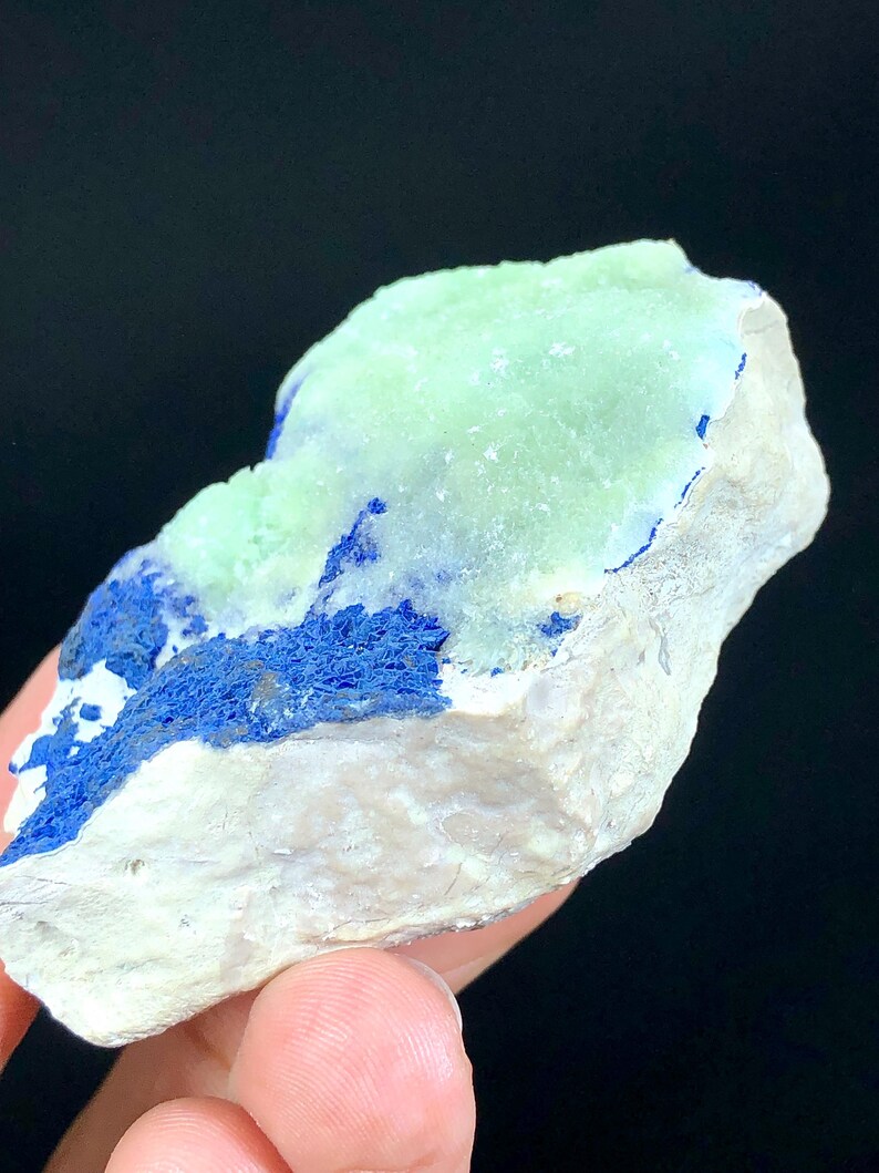 May include: A rough, natural rock specimen with a light green mineral on top and a dark blue mineral on the bottom.