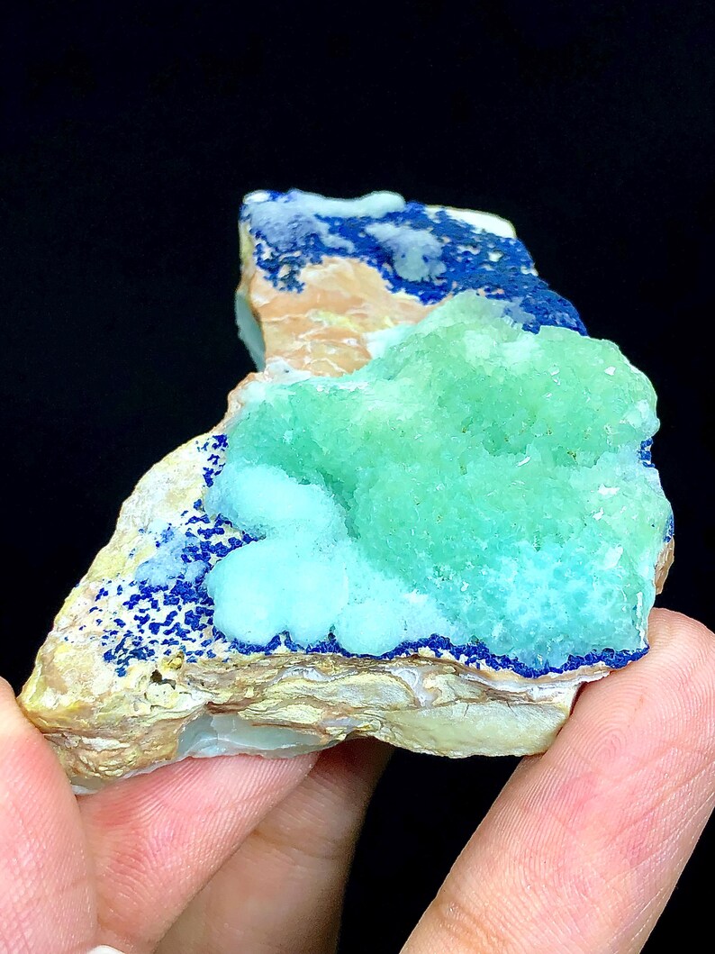 May include: A close-up of a blue and green mineral specimen. The specimen has a rough, textured surface and is composed of several different layers. The blue layer is on the top and bottom of the specimen, while the green layer is in the middle. The specimen is about 3 inches long and 2 inches wide.