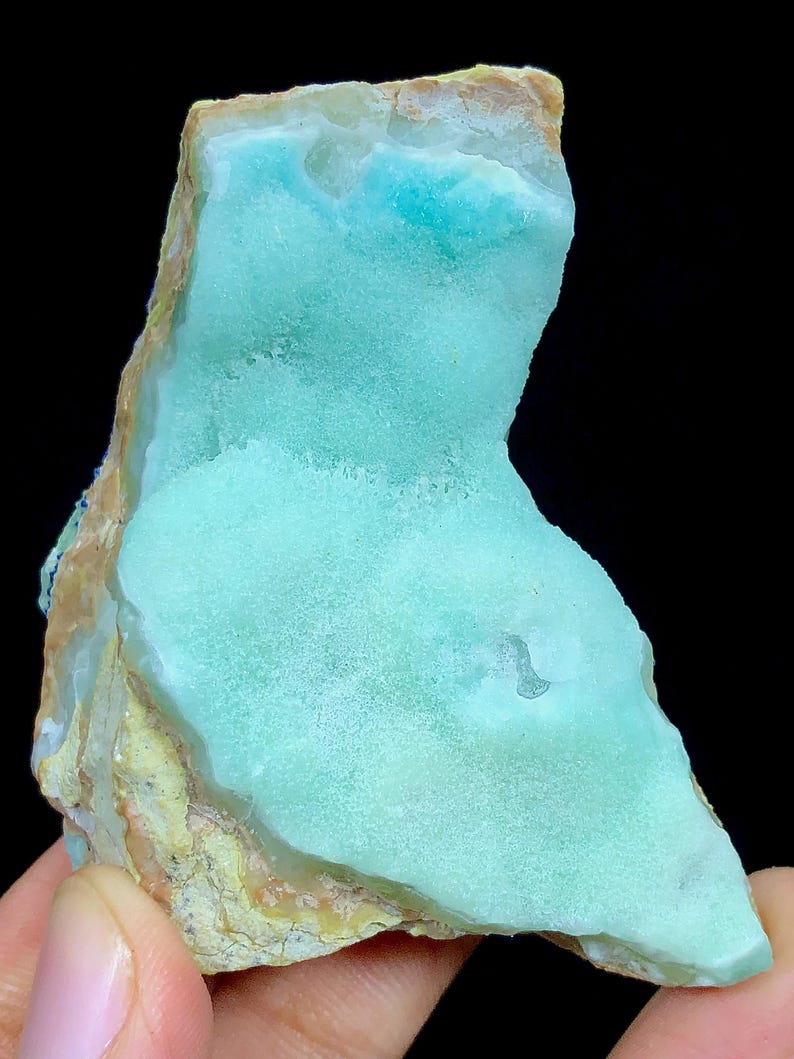 May include: A light blue and green, irregularly shaped, polished, natural stone with a rough, brown exterior.