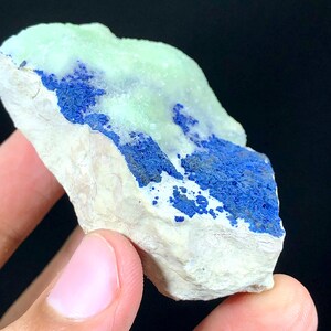May include: A rough, white rock with a blue and green mineral deposit. The mineral is a vibrant blue color and has a rough, crystalline texture. The green mineral is a lighter shade and has a smooth, glassy texture.