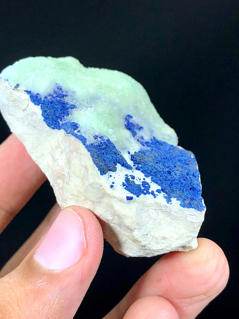 May include: A rough, white rock with a blue and green mineral deposit. The mineral is a vibrant blue color and has a rough, crystalline texture. The green mineral is a lighter shade and has a smooth, glassy texture.
