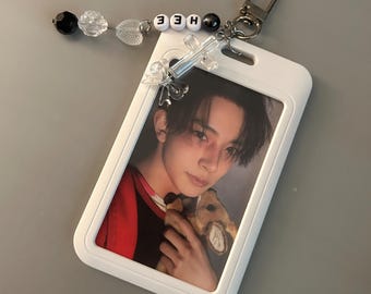 May include: White ID badge holder with a photo of a person holding a stuffed animal. The holder is attached to a beaded keychain with the name "HEE" spelled out in white letter beads.