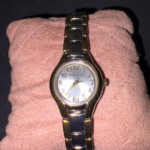 Reloj de vestir para mujer Anne Klein 10/6777SVTT de dos tonos con esfera plateada y fecha.