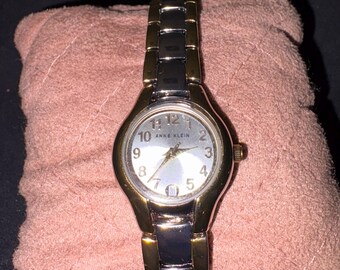 Reloj de vestir para mujer Anne Klein 10/6777SVTT de dos tonos con esfera plateada y fecha.