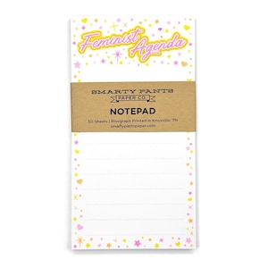 May include: A notepad with a pink and yellow border featuring stars and hearts. The notepad has the text "Feminist Agenda" in pink and yellow letters. The notepad is labeled "SMARTY PANTS PAPER CO. NOTEPAD 50 Sheets | Risograph Printed in Knoxville, TN smartypantspaper.com"